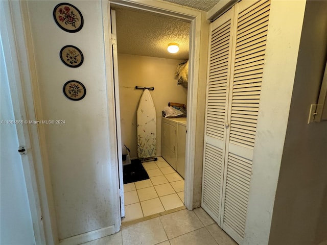 clothes washing area featuring a textured ceiling, independent washer and dryer, and light tile patterned flooring