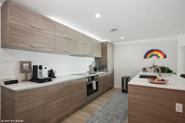 kitchen featuring light hardwood / wood-style flooring, black electric cooktop, sink, and stainless steel oven