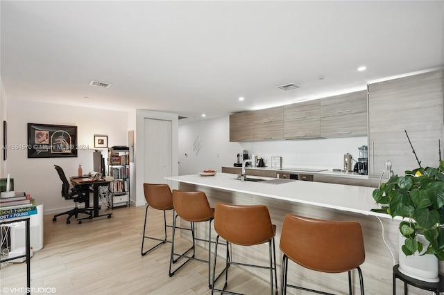 kitchen with a kitchen bar, sink, and light hardwood / wood-style floors