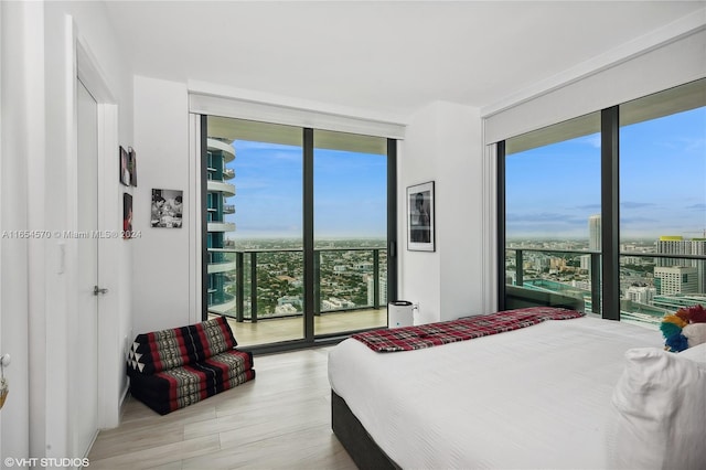 bedroom with multiple windows, expansive windows, and light hardwood / wood-style flooring