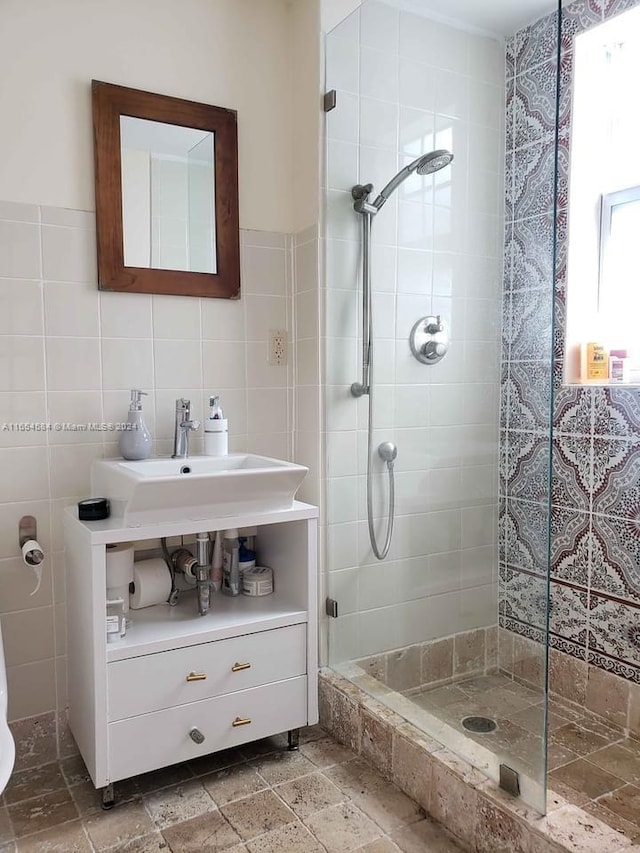 bathroom with tile walls, vanity, and a tile shower