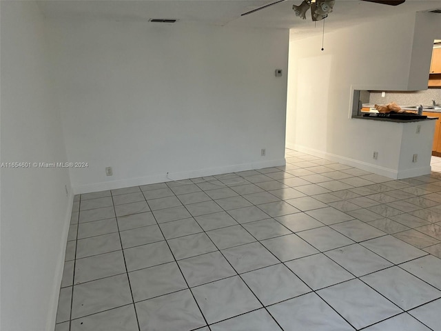 tiled empty room featuring ceiling fan