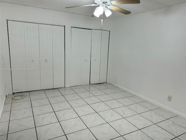 unfurnished bedroom with ceiling fan and two closets