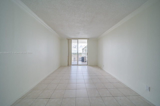 spare room featuring a textured ceiling, crown molding, and light tile patterned floors