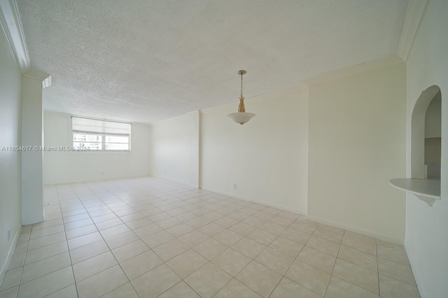 tiled empty room with crown molding and a textured ceiling