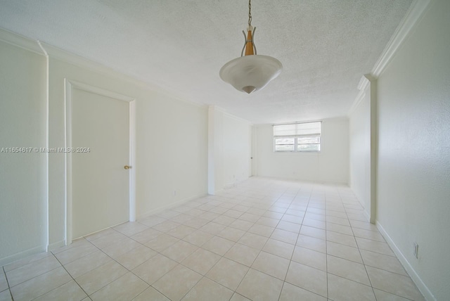 spare room with light tile patterned flooring, a textured ceiling, and ornamental molding