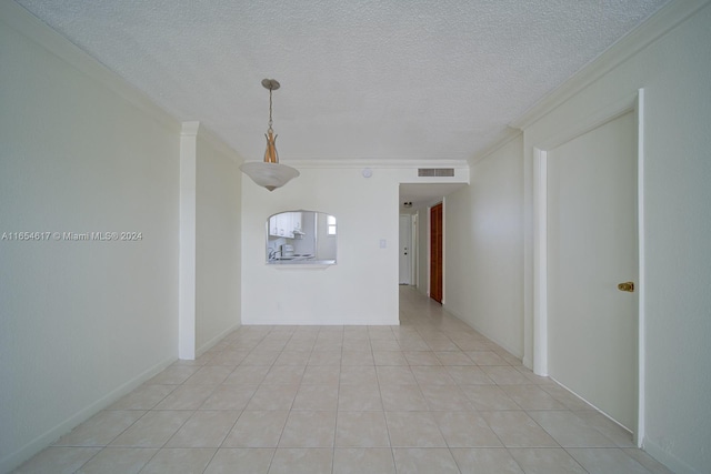 unfurnished room featuring a textured ceiling, crown molding, and light tile patterned flooring