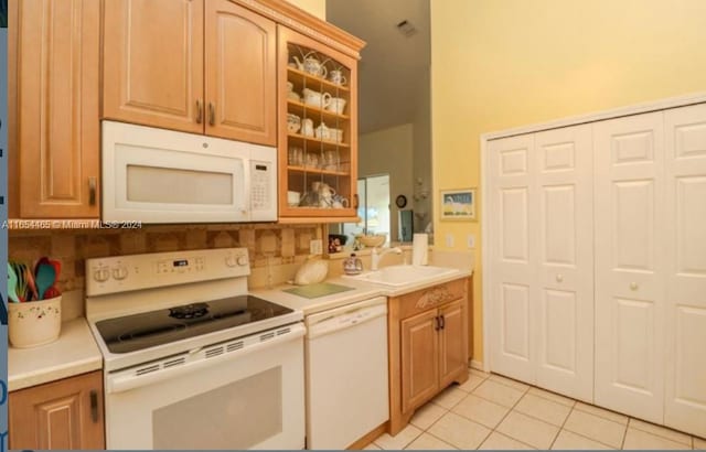 kitchen featuring light tile patterned floors, backsplash, sink, and white appliances