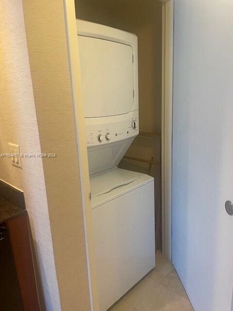 washroom with stacked washer and clothes dryer and light tile patterned floors