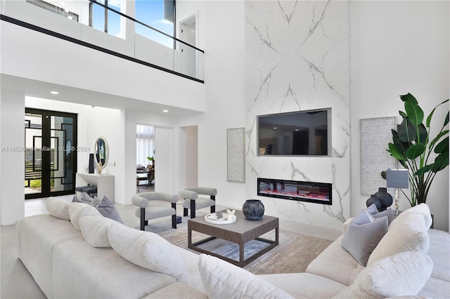 living room featuring a high end fireplace, a healthy amount of sunlight, and a high ceiling