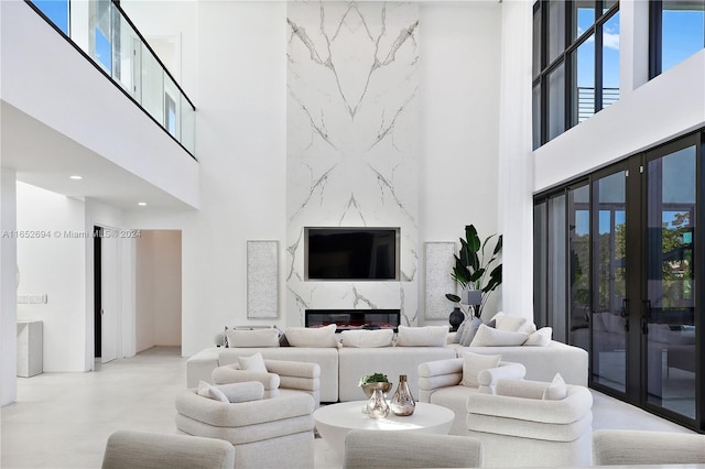 living room with a high end fireplace, french doors, and a towering ceiling