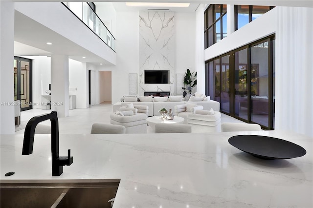 living room with a fireplace, a towering ceiling, and sink