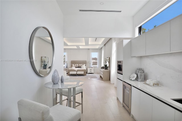 kitchen with a wealth of natural light, white cabinets, and light hardwood / wood-style floors