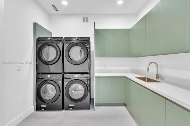 clothes washing area featuring cabinets, stacked washing maching and dryer, sink, and washing machine and dryer