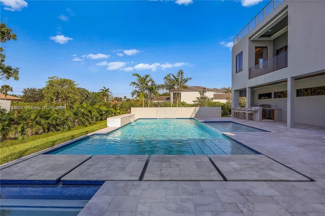 view of pool with a jacuzzi, a patio, and exterior kitchen