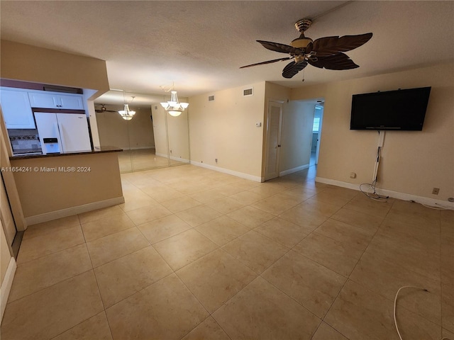 unfurnished living room with visible vents, light tile patterned floors, baseboards, a textured ceiling, and ceiling fan with notable chandelier