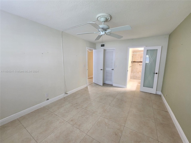 interior space with baseboards, a ceiling fan, light tile patterned flooring, and a textured ceiling