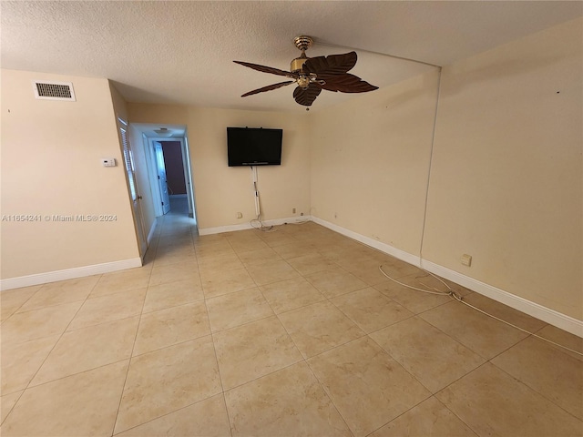 spare room featuring visible vents, baseboards, light tile patterned floors, a ceiling fan, and a textured ceiling
