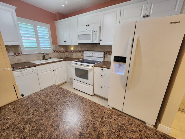 kitchen with white appliances, white cabinetry, dark countertops, decorative backsplash, and a sink