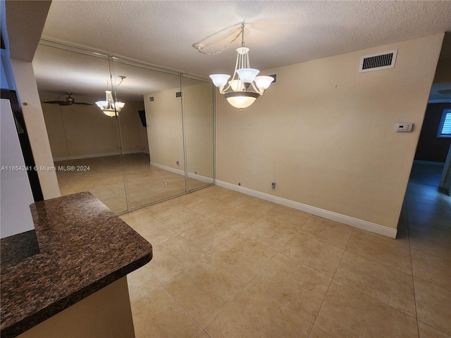 unfurnished dining area with visible vents, baseboards, a notable chandelier, and a textured ceiling