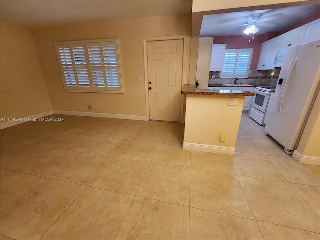 kitchen featuring white appliances, a peninsula, light tile patterned floors, white cabinets, and ceiling fan