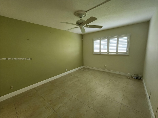 unfurnished room with light tile patterned floors, baseboards, and a ceiling fan