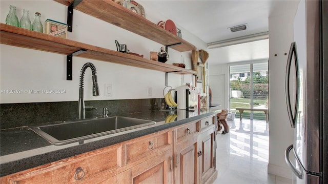 kitchen featuring dark countertops, visible vents, open shelves, freestanding refrigerator, and a sink