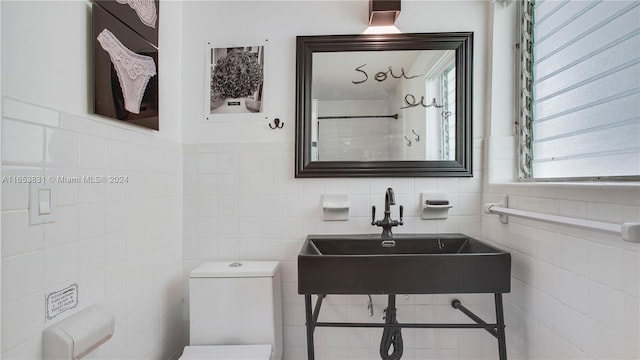 bathroom featuring tile walls, toilet, and a sink