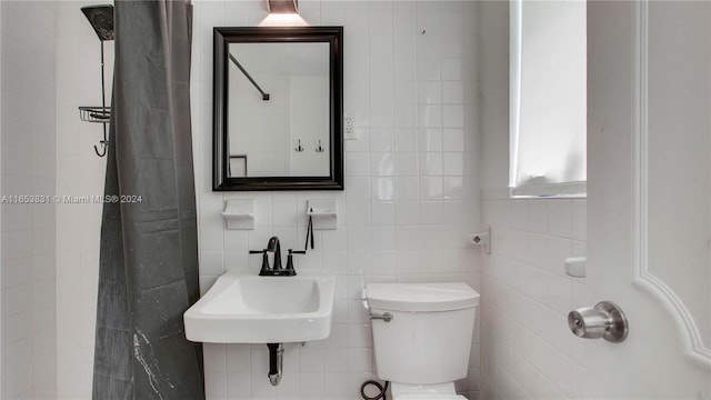 bathroom with tile walls, toilet, tasteful backsplash, and a sink