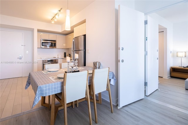 dining space featuring rail lighting and light hardwood / wood-style floors