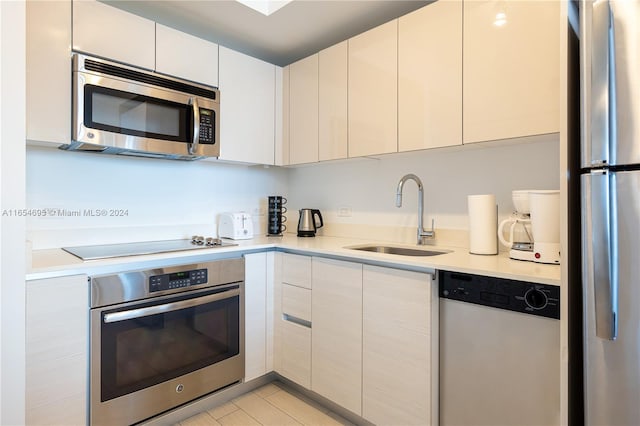 kitchen featuring white cabinets, light tile patterned floors, stainless steel appliances, and sink