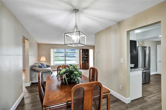 dining space with a textured ceiling, a chandelier, and dark hardwood / wood-style flooring