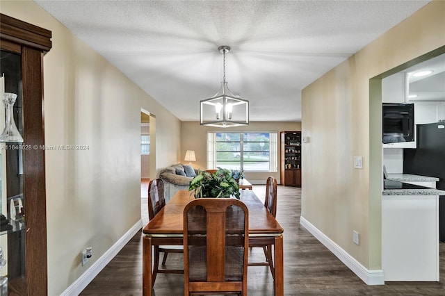 dining area with a textured ceiling, a notable chandelier, and dark hardwood / wood-style flooring