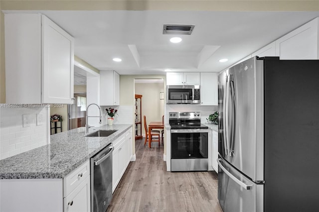 kitchen with light wood-type flooring, appliances with stainless steel finishes, sink, and white cabinets