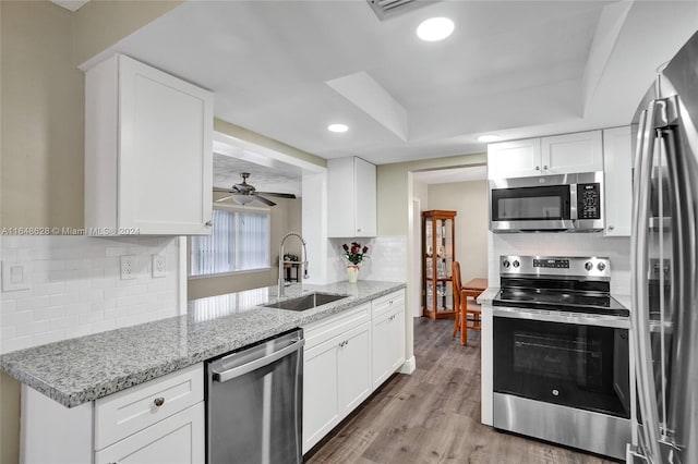 kitchen featuring appliances with stainless steel finishes, sink, ceiling fan, light wood-type flooring, and white cabinets