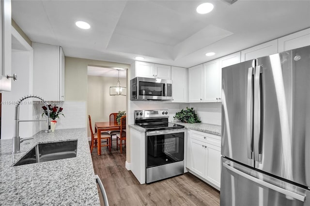 kitchen featuring white cabinets, hardwood / wood-style floors, appliances with stainless steel finishes, sink, and a raised ceiling