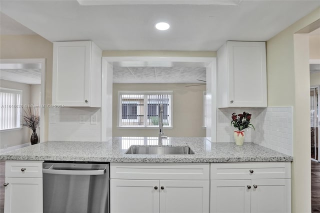 kitchen with stainless steel dishwasher, sink, light stone countertops, and tasteful backsplash