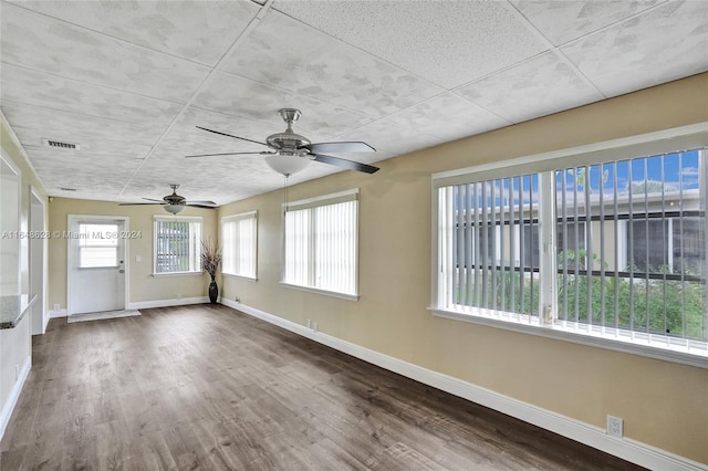 spare room with a wealth of natural light, hardwood / wood-style floors, and ceiling fan