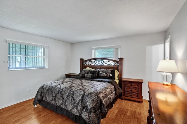 bedroom with a textured ceiling and light hardwood / wood-style floors