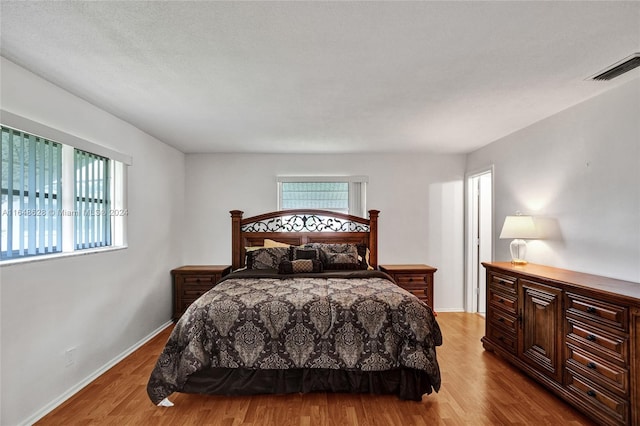 bedroom with light wood-type flooring and a textured ceiling