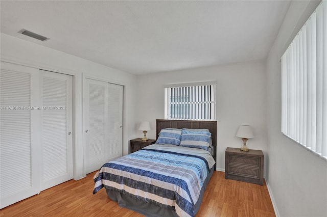 bedroom featuring light wood-type flooring and multiple closets