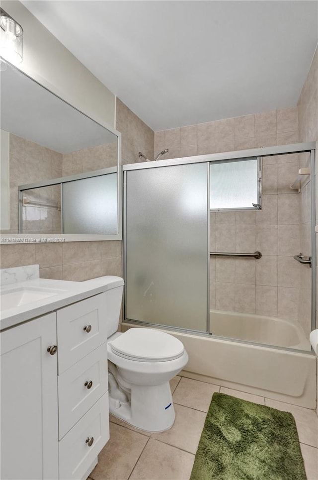 full bathroom featuring tile patterned flooring, toilet, combined bath / shower with glass door, tile walls, and vanity