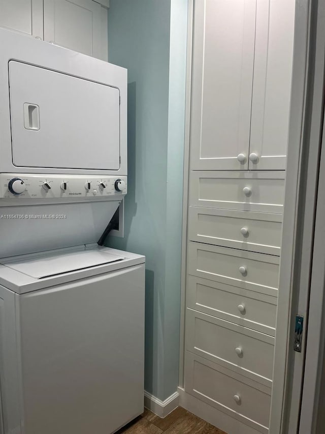 laundry room featuring dark wood-type flooring and stacked washer / drying machine