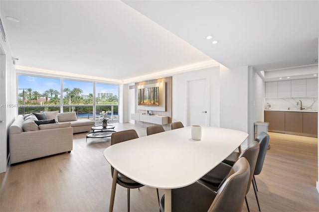 dining area with light hardwood / wood-style flooring, expansive windows, and sink