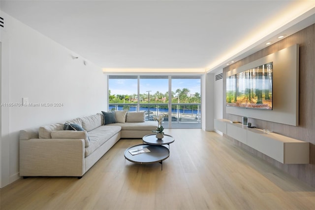 living room featuring light wood-type flooring and a wall of windows