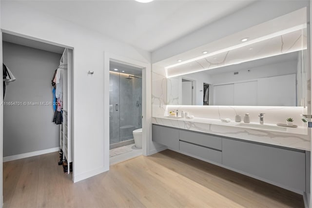 bathroom featuring toilet, wood-type flooring, an enclosed shower, and vanity