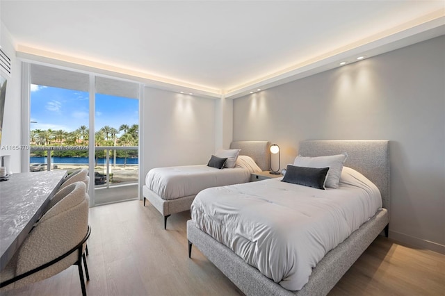 bedroom featuring access to exterior, wood-type flooring, and a water view