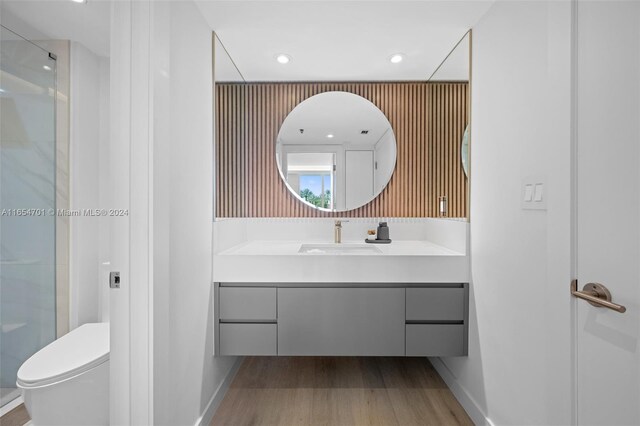 bathroom featuring vanity, toilet, hardwood / wood-style floors, and a shower with shower door