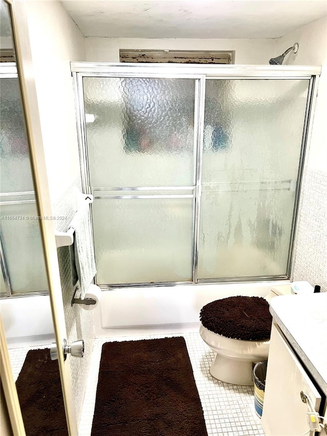 full bathroom with shower / bath combination with glass door, vanity, toilet, and tile patterned floors