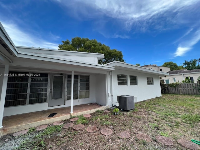 back of property featuring central AC unit, a yard, and a patio area